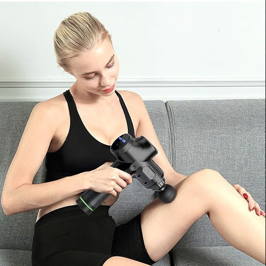 Pistolet de massage tenu par femme blonde sur intérieur de cuisse