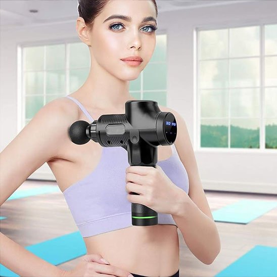 Pistolet de massage tenu par femme sur épaule