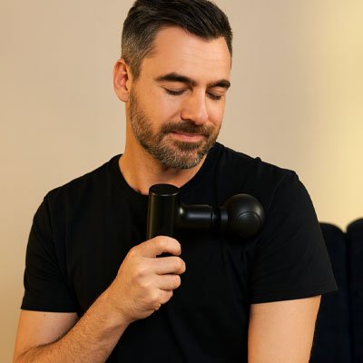 Pistolet de massage tenu par homme épaule